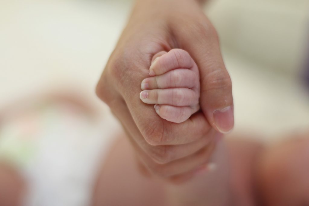 Eine erwachsene Hand hält eine Babyhand